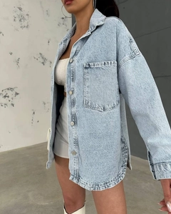 Detailed close-up of light blue washed denim jacket featuring a classic pocket and metal button