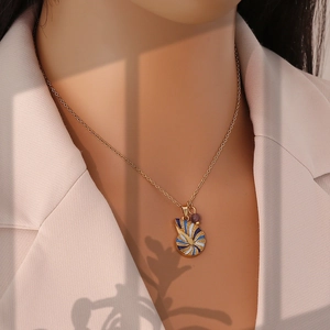 Detail of gold necklace with blue and white enamel pendant on a fashion model