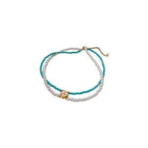 Double-layered necklace with turquoise beads, white pearls, and a clover pendant charm