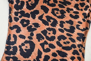 Macro view showing the detailed leopard print pattern on smooth synthetic fabric