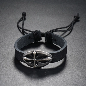 Macro detail of adjustable punk leather bracelet featuring a retro metal cross charm
