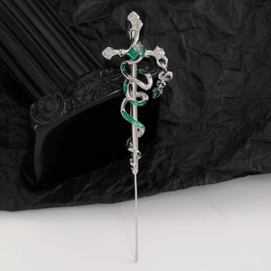 Macro view of gothic snake wrapped sword pin with green crystal and enamel inlay