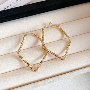 Detail of square gold hoop earrings with glitter texture in a velvet jewelry box