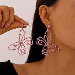 Detail of pink rhinestone butterfly earrings with hollow design on hand and model