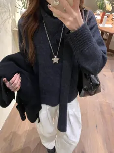 Détail d'un collier pendentif étoile porté sur un pull à col roulé gris foncé pour femme