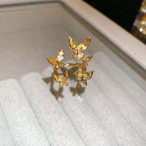 Macro detail of gold plated multi-butterfly ring with white enamel wing accents