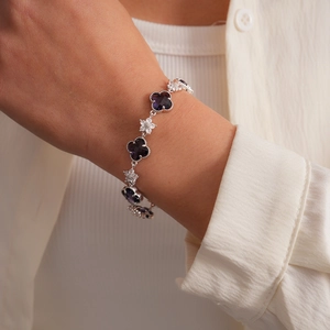 Détail d'un bracelet en zircon avec trèfles violets et fleurs blanches au poignet