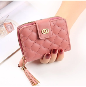 Gros plan d'un portefeuille matelassé rose pour femme avec boucle dorée et pompon