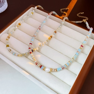 Close-up of colorful seed bead necklaces with baroque pearls and golden metal accents