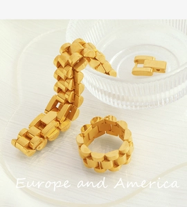Detailed view of golden Jubilee style chain bracelet and matching ring on textured glass