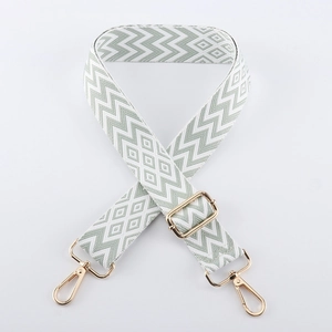 Adjustable wide woven bag strap with green and white geometric patterns and gold buckles