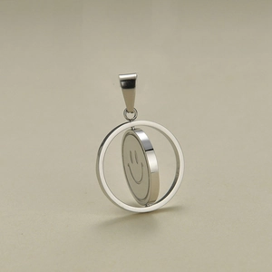 Close-up of a rotating silver stainless steel pendant with an engraved smiley face icon