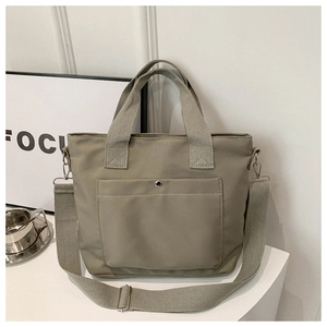 Detalle del bolso tote de nailon caqui con bolsillo frontal, botón metálico y correa ancha