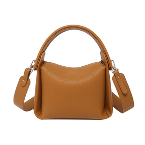 Brown leather crossbody bag with wide shoulder strap and soft minimalist pillow shape