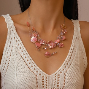 Close-up of bohemian layered beaded necklace with pink shells and silver beads