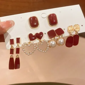 Detail view of red pearl earring set with gold accents and vintage heart designs