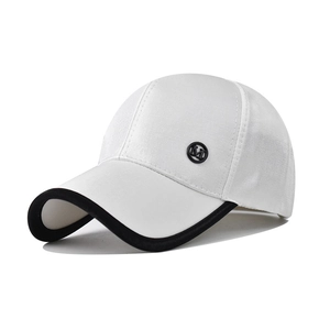 Detailed shot of white baseball cap with black brim and metallic M letter badge