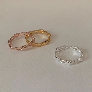 Detail of three minimalist heart-shaped open rings in gold, silver, and rose gold finishes