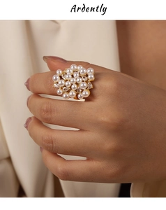 Détail d'une bague dorée de luxe avec perles blanches et zircons sur la main