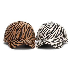 Detail of zebra and tiger print baseball caps showing fabric texture and curved brim