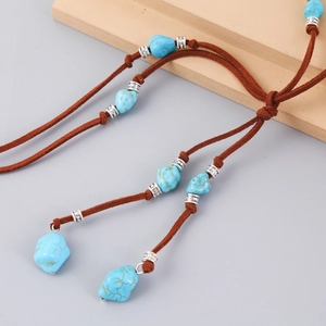 Detail of bohemian necklace with turquoise stones and silver-carved beads on suede cord
