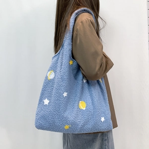 Blue faux shearling tote bag with cartoon stars shown on model for autumn winter style