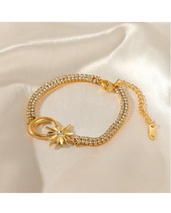 Dettaglio del bracciale placcato oro 14K con ciondoli luna e stella su sfondo di seta