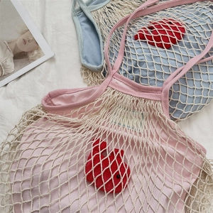 Dettaglio delle borse a rete intrecciate rosa e blu con ciondolo a coniglio rosso