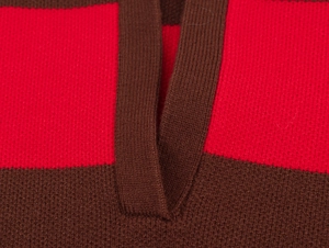 Vue macro de l'encolure en V montrant la texture du tricot à rayures rouge et marron