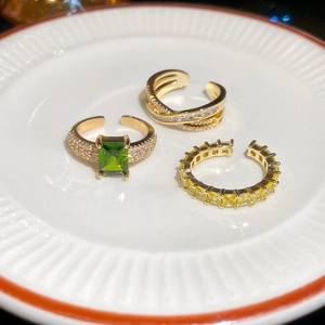 Detailed close-up of 18k gold plated rings with green and yellow cubic zirconia stones