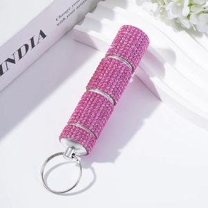 Close-up of a pink rhinestone-studded pill box keychain on a luxury lifestyle tray