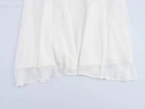 Détail de la texture en mousseline blanche translucide et plis de l'ourlet de robe