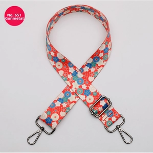 Detail of adjustable gunmetal hardware and red floral pattern webbing bag strap