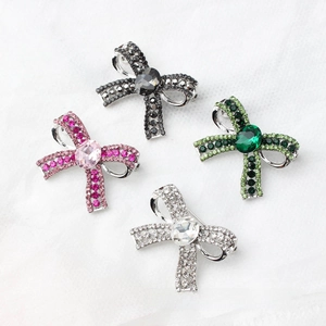 Close-up of bow brooches in pink, green, black and silver with sparkling crystals