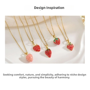Macro detail of strawberry enamel pendants on golden chains in red and pink colors