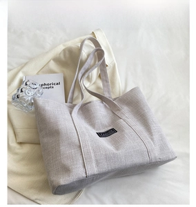 Close-up of off-white canvas tote bag featuring fashion patch and linen texture details