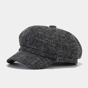 Close-up of black and white houndstooth tweed fabric texture on a classic newsboy cap