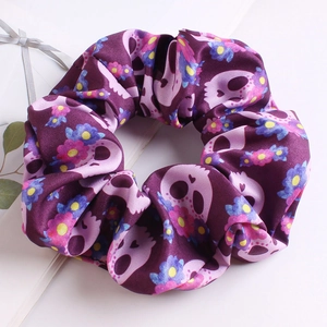 Detail of purple fabric scrunchie with pink skull and colorful floral print patterns