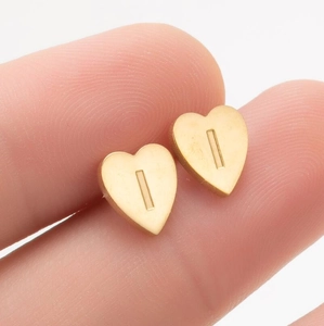 Détail d'une boucle d'oreille cœur en or brossé avec la lettre I gravée sur acier inoxydable