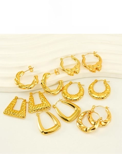 Flat lay of vintage golden bow earrings and twisted metal hoops on white texture