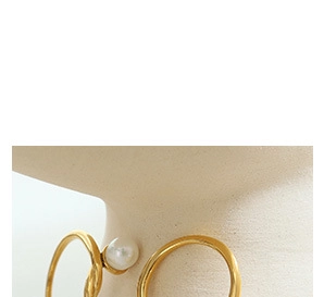 Detailed close-up of a gold-plated flower charm earring featuring a white pearl accent
