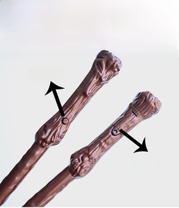 Detail of the magic wand handle showing the power switch button and battery compartment