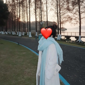 Lifestyle shot of a thick light blue mohair scarf with tassels and a white plush coat