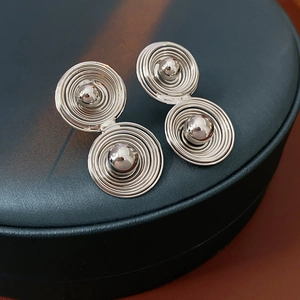 Dettaglio macro di orecchini a spirale in argento con perle su espositore testurizzato