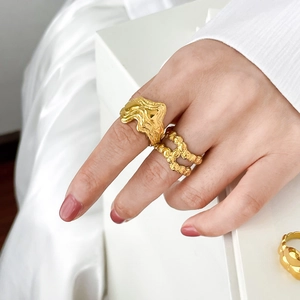 Detailed close-up of 18K gold-plated fluid lava and woven texture rings on a hand