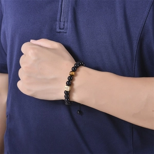 Detail of beaded bracelet with black onyx, tiger eye stone, and golden A-Z zircon cube