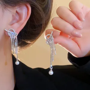 Macro shot of silver tassel earrings featuring sparkling zircons and white pearl drops