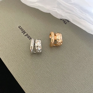 Detailed view of silver and rose gold double-layered ear cuffs on textured paper