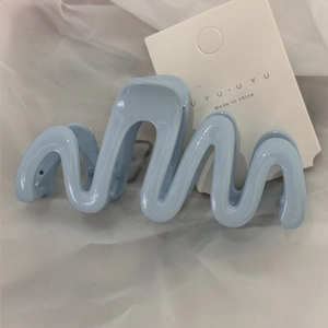 Detail of light blue wave-shaped claw clip showing smooth material and spring mechanism