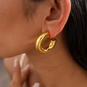 Detailed close-up of a gold-finish C-shaped earring with elegant textured threaded surface